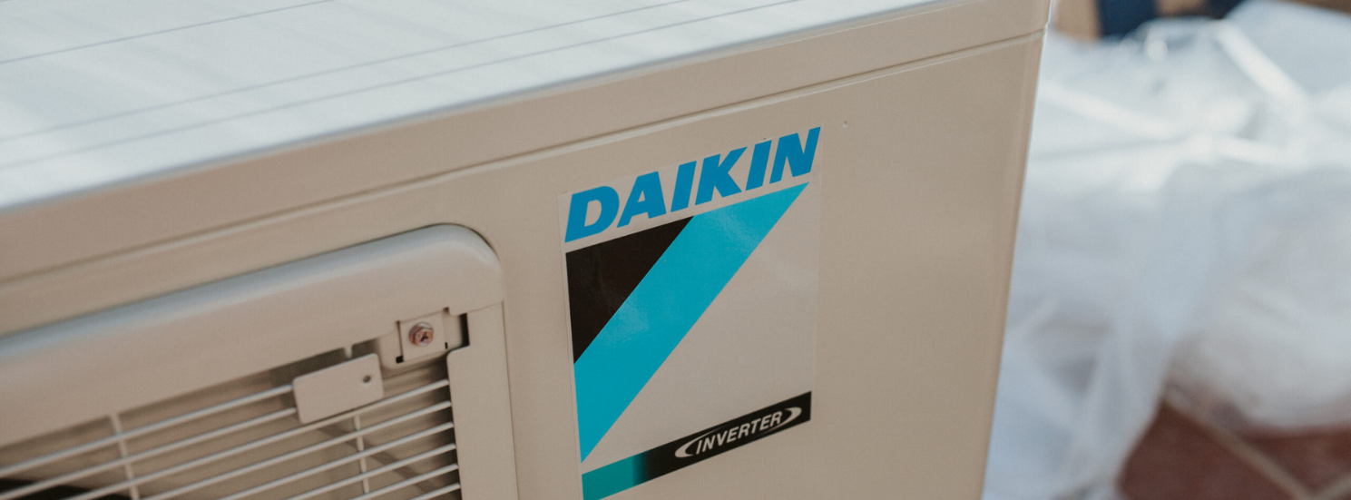 daiken banner Outdoor Daikin air conditioning unit installed beside a residential home, part of a high-efficiency cooling system.